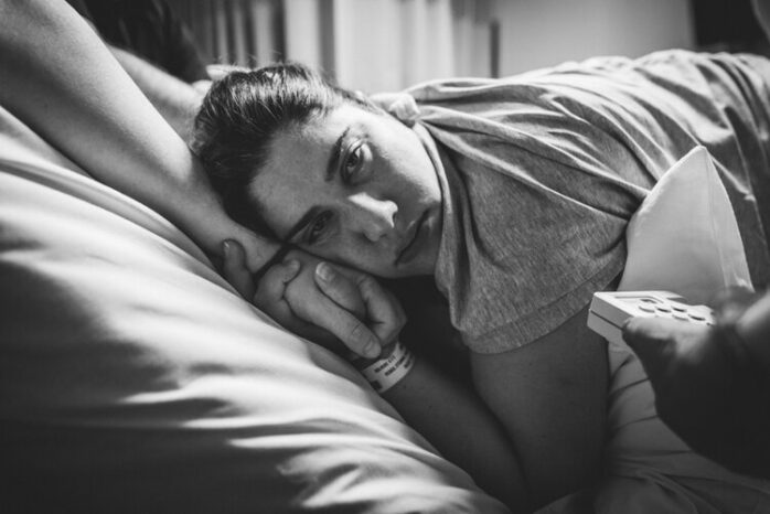 Vrouw kijkt in de camera tijdens het opvangen van weeën