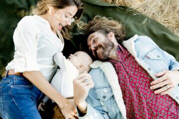 Ouders liggen met baby in het gras en lachen