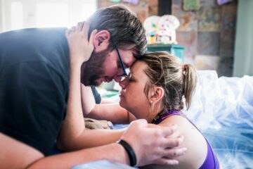 Zwangere vrouw zit in de overgangsfase van haar bevalling en houdt haar partner stevig vast