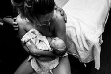 Net bevalling vrouw haalt haar pasgeboren baby vast na de uitdrijvingsfase