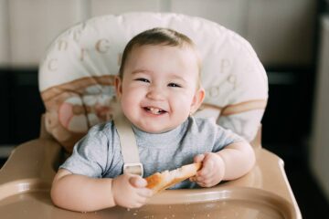 Baby eet brood in kinderstoel