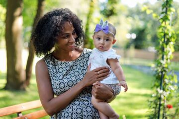 Moeder met baby buiten in warm weer, ze heeft haar baby luchtig gekleed