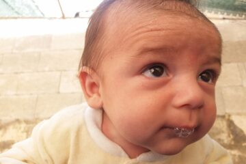 Close-up van baby die bezig is met bellen blazen met zijn lippenblowing raspberries