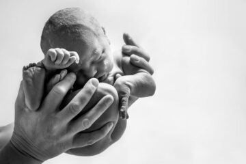 Pasgeboren baby wordt in foetushouding vastgehouden