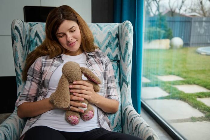 Vrouw houdt knuffel vast op buik