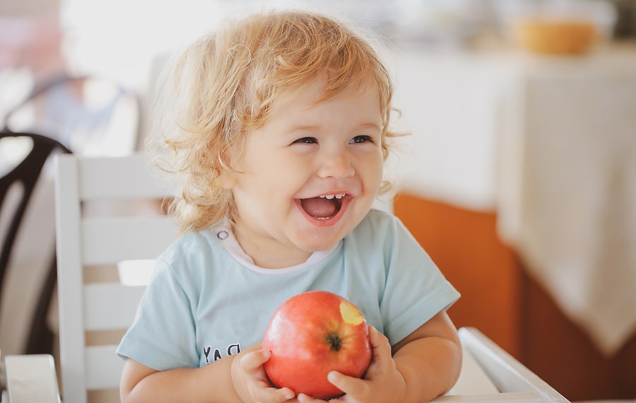 Peuter lacht en eet appel