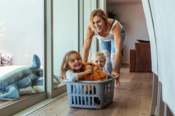Moeder duwt een wasmand waar haar twee kinderen in zitten