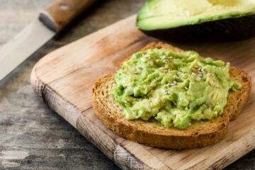 Een houten plank met een boterham met geprakte avocado erop voor je baby