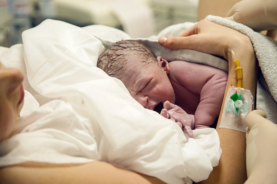 Neugeborenes kurz nach der Entbindung bei Mutter auf der Brust