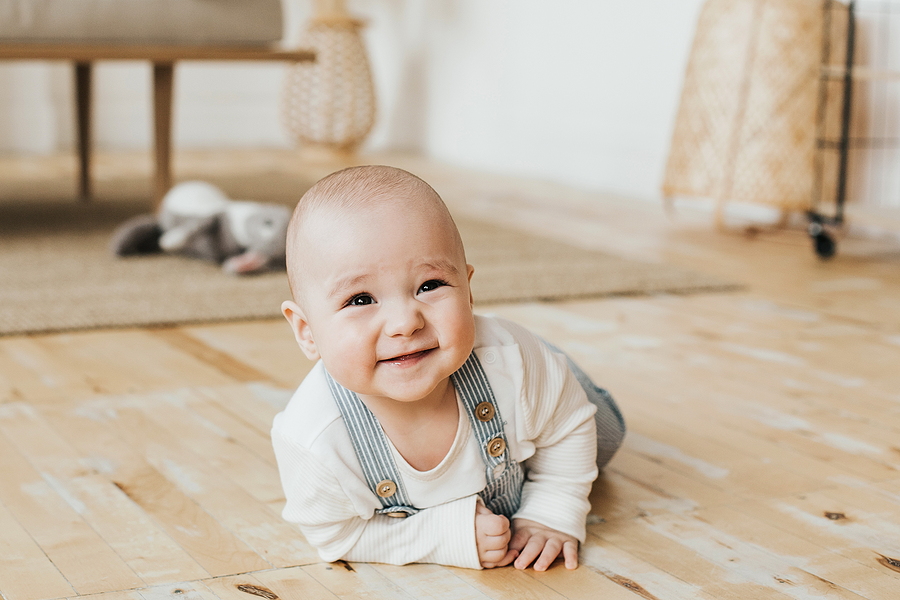 Baby 24 Wochen alt krabbelt auf dem Boden und strahlt