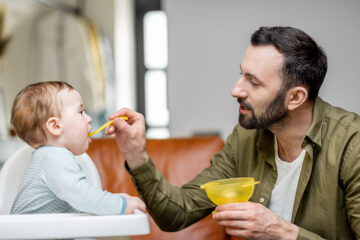 Beikoststart: Vater fütter sein fünf Monate altes Baby liebevoll.