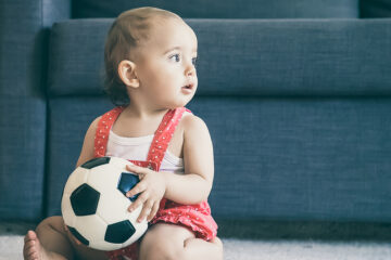 Mädchennamen 2022 - Baby sitzt und hat einen Ball in der Hand