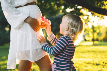 Schwangerschaftshormone- Mutter spielt mit ihrem Kind und ist schwanger