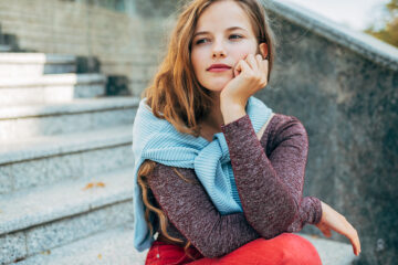 Einnistungsblutung - Frau sitzt auf einer Treppe und schaut in die Ferne