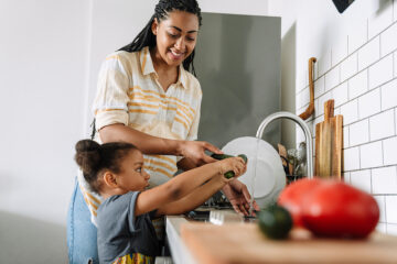 Listeriose: schwangere Mutter wäscht mit ihrer Tochter vor dem kochen das Gemüse