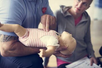 Erste Hilfe bei Babys. Vorführung einer Herzdruckmassage bei einem Erste Hilfe Kurs.