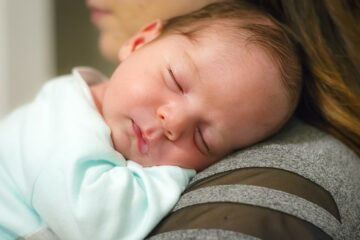 Baby schläft auf der Schulter der Mutter