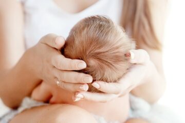 Mutter hat den Kopf ihres Babys in den Händen