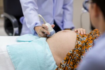 Fruchtwasseruntersuchung, Arzt schallt den Bauch einer Schwangeren