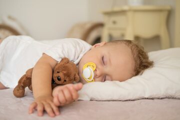 Baby schläft mit einem Teddy im Arm