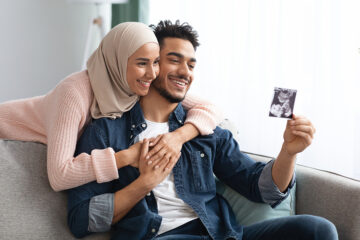 Geschlecht erkennen: Ein glückliches Paar schaut sich das Ultraschallbild an.