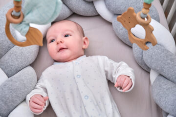 Jungennamen 2023: Baby liegt auf dem Rücken und spielt mit Mobile.