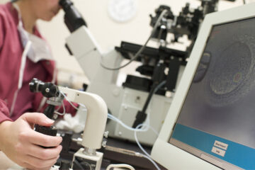 ICSI: Labormittarbeiterin befruchtet eine Eizelle unter dem Mikroskop.