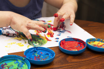 Kleinkind malt ein Bild zum Vatertag mit Fingerfarben.