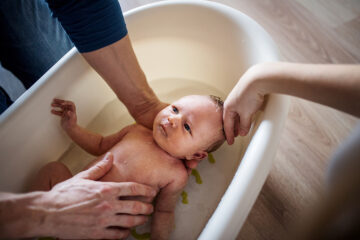Babys erstes Bad: Eltern baden ihr Baby in einer Babybadewanne