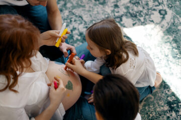 Familie bemalt zusammen den Babybauch.