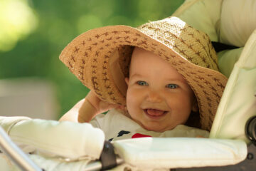 Baby mit Sonnenhut im Kinderwagen