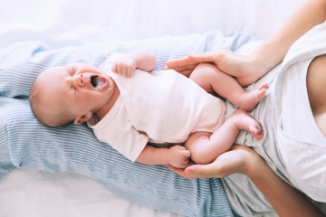 Mama hält Baby mit Mundsoor auf dem Schoß