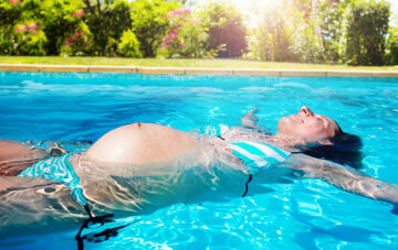 Schwanger im Sommer Frau liegt schwanger im Pool auf dem rücken und entspannt sich
