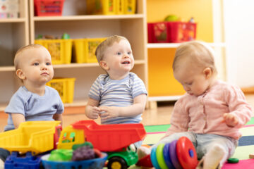 Babys spielen nebeneinander in einer Kinderkrippe