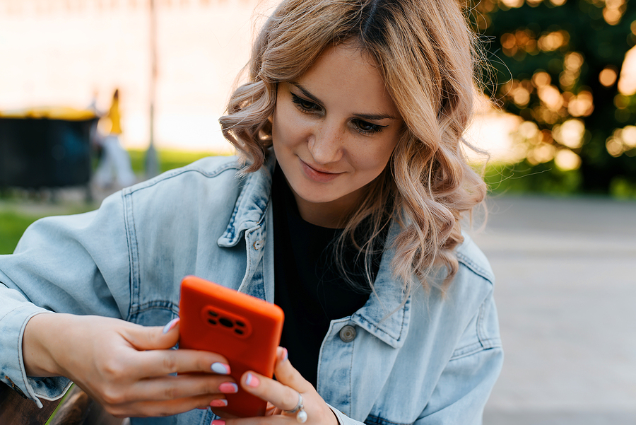 Frau guckt lächelnd auf ihr Handy