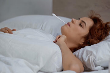 Frau misst ihre Temperatur für die natürliche Familienplanung.