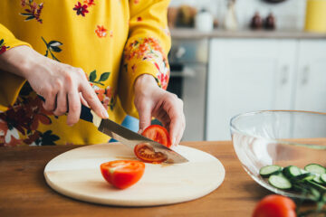 Schwangere schneidet Tomaten gegen Schwangerschaftsbeschwerden.