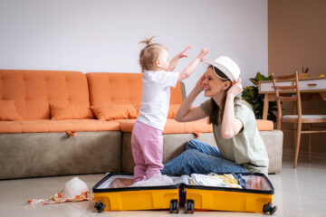 Packliste Babyurlaub: Mama packt ihren Koffer und hat Spaß mit Baby.