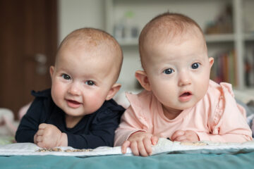 Zwei süße Babys schauen in die Kamera. Babynamen 2024.